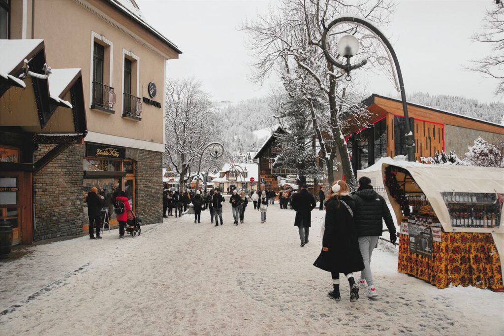 Snow-covered street in Zakopane, Poland, bustling with people.
